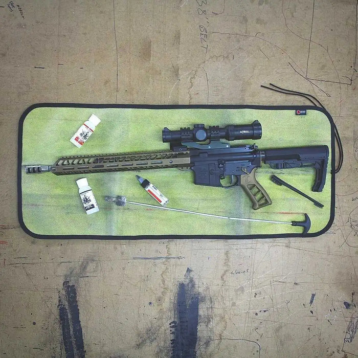 Drop Zone Mat — Yellow Black variant in use during firearm cleaning on a wood bench.